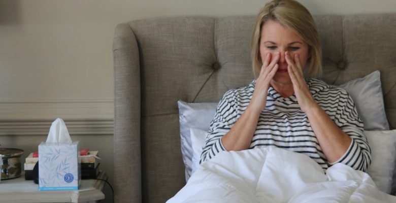 Treating a sinus infection without antibiotics, natural remedies that work. Photo of a sick woman in bed by Nicole Johnson. | Jennifer Margulis